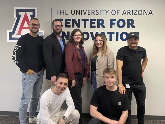 seven people posing in front of a university of arizona center for innovation sign