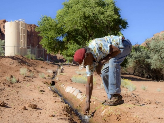 a man leaning over a small stream of water on the Navajo Nation