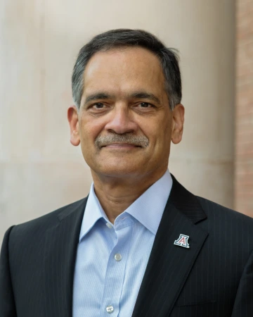 Suresh Garimella outside in a dress shirt and blazer with a U of A Block A pin on his lapel. 